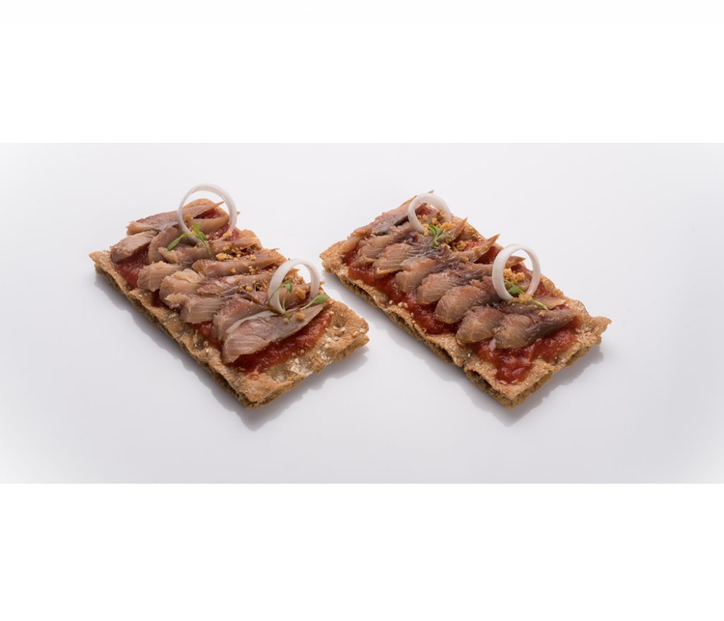 Tostas de arencon ahumado con tomate, aros de cebolla y hierbas aromáticas