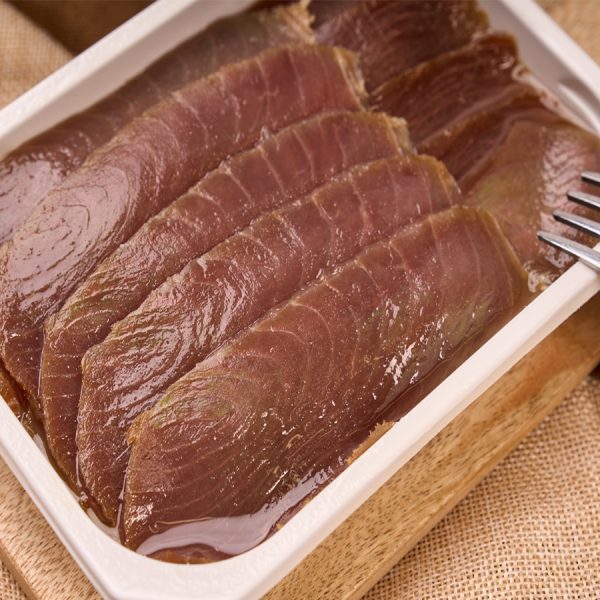 Bandeja abierta de lonchas de atun ahumado en aceite