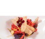 Filetes de melva canutera con pimientos rojos, ajo, hojas verdes y una flor comestible