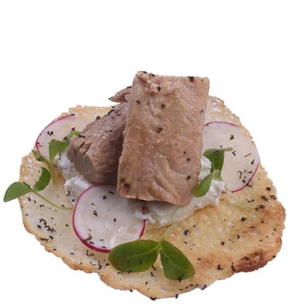 Filetes de melva sobre una base crujiente con queso, rábano y brotes verdes