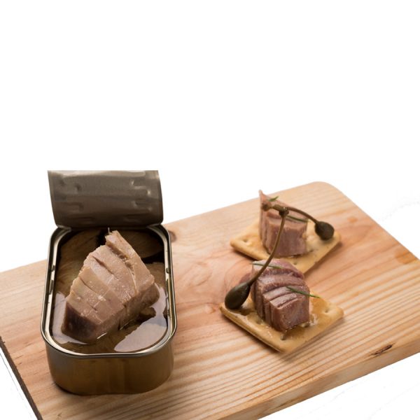 Lata de ventresca de atun en aceite de oliva abierta sobre tabla de madera