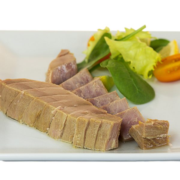 Plato de ventresca de atún cocida acompañada de hojas de lechuga y cherrys